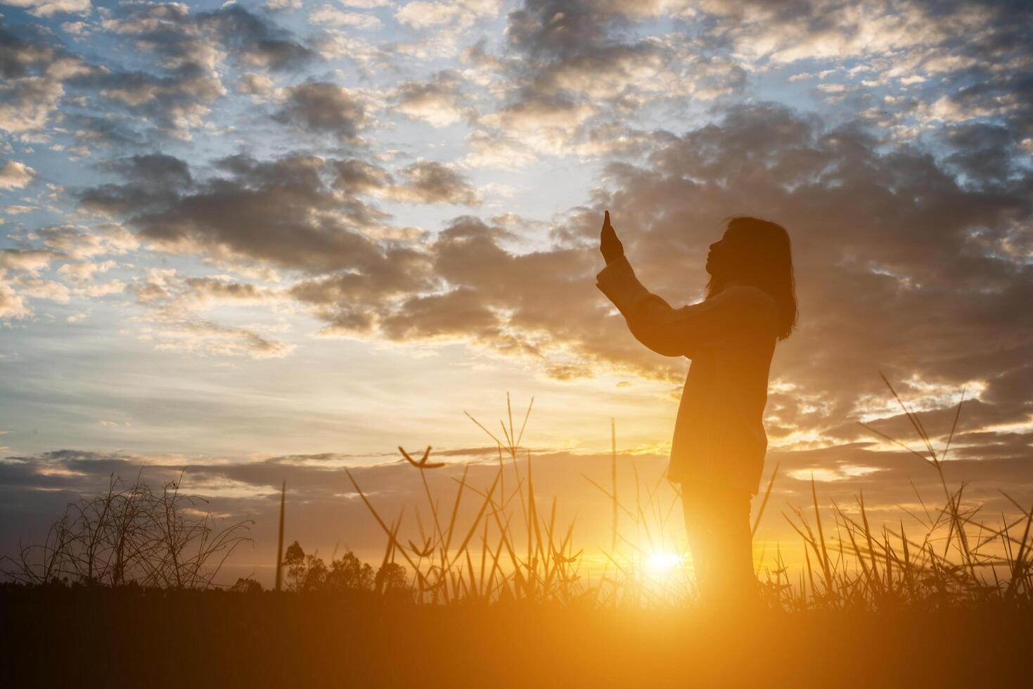 silueta de mujer reza durante la puesta de sol. foto