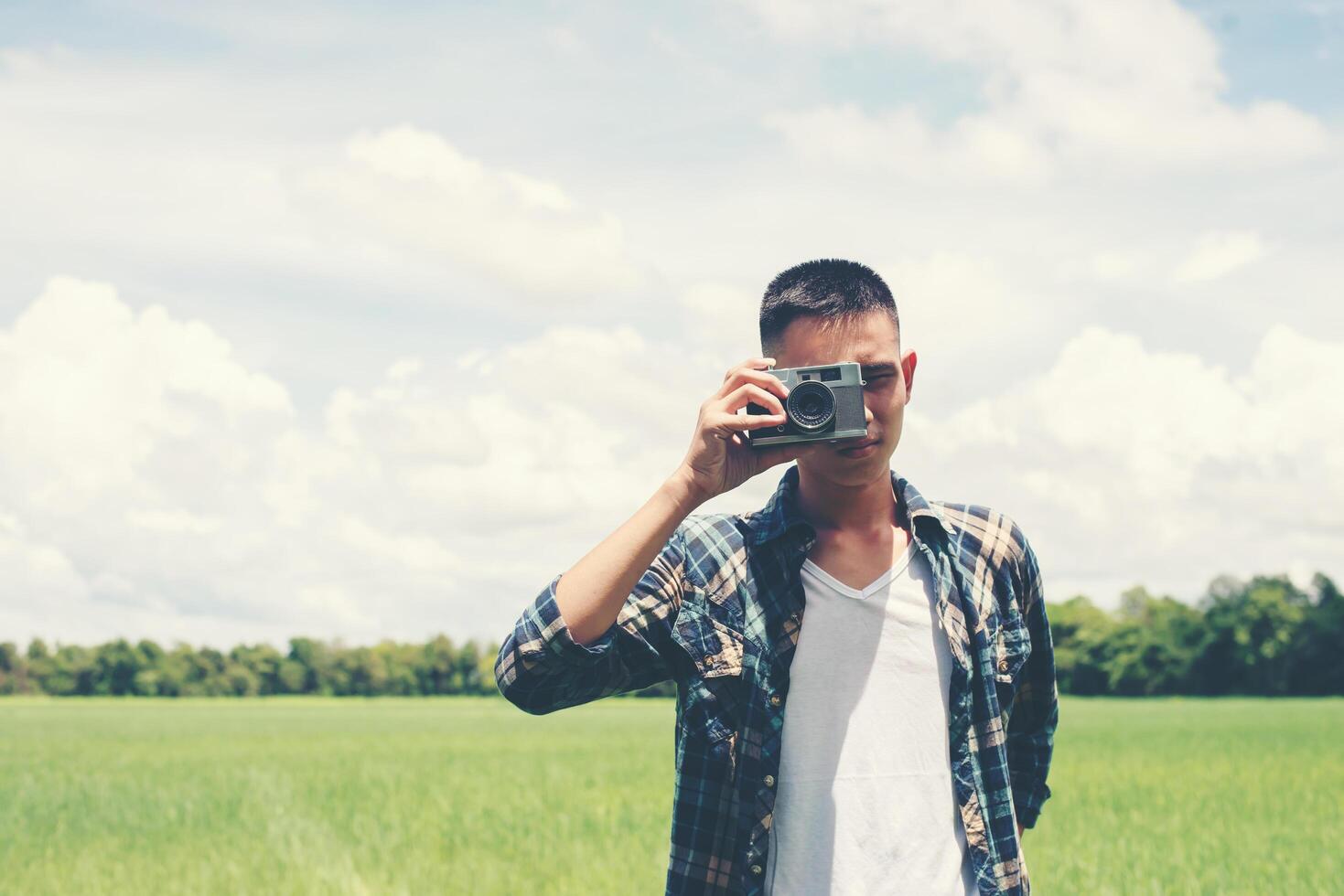 Young hipster handsome man photography standing shooting retro camera with nature enjoy and happy at grassland. photo