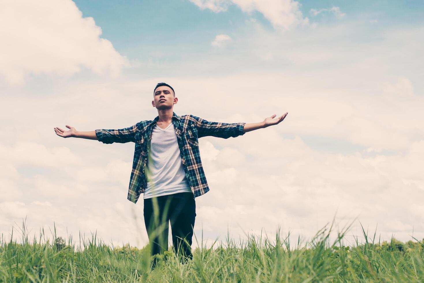 Freedom Young teenage man stretching his arms into the sky enjoy and happy with fresh air at grassland. photo