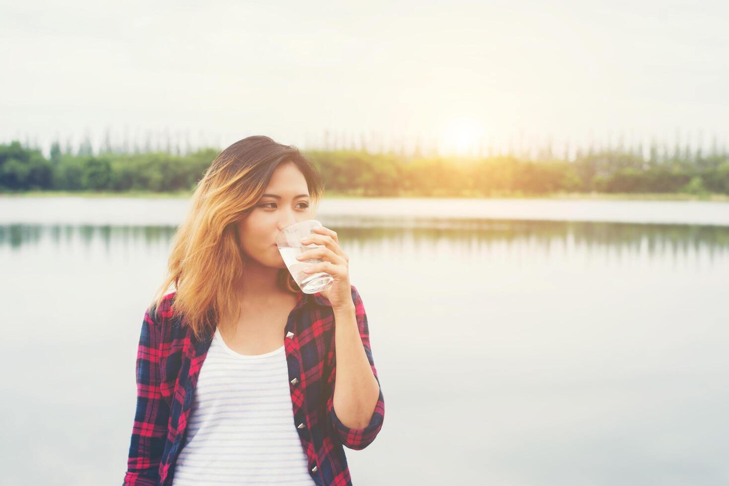 young beautiful hipster woman drinking water standing on pier, relaxing enjoy with nature. photo