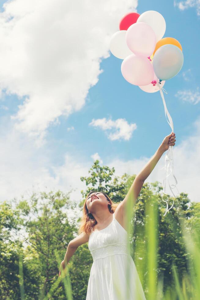 una joven y hermosa mujer asiática sosteniendo un globo de colores disfruta con aire fresco se ve tan feliz. foto