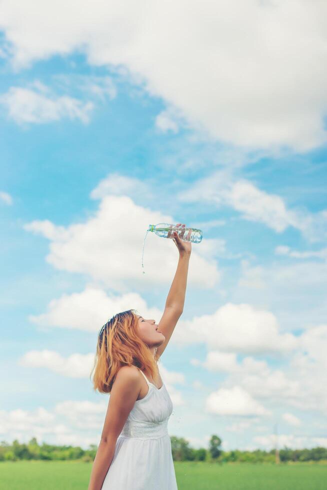 Young woman in park pours water over a face for freshing at grassland enjoy and happy life. photo