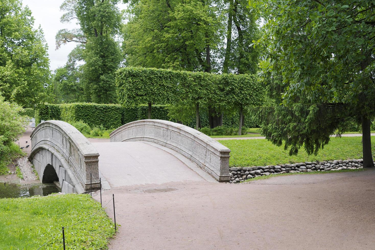 puente de piedra con un arco sobre el arroyo en el parque de verano. foto