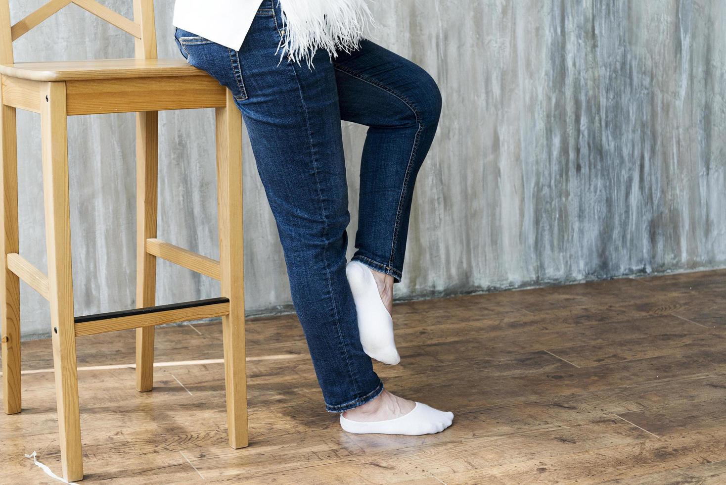 piernas en jeans en la silla alta de la niña embarazada. foto