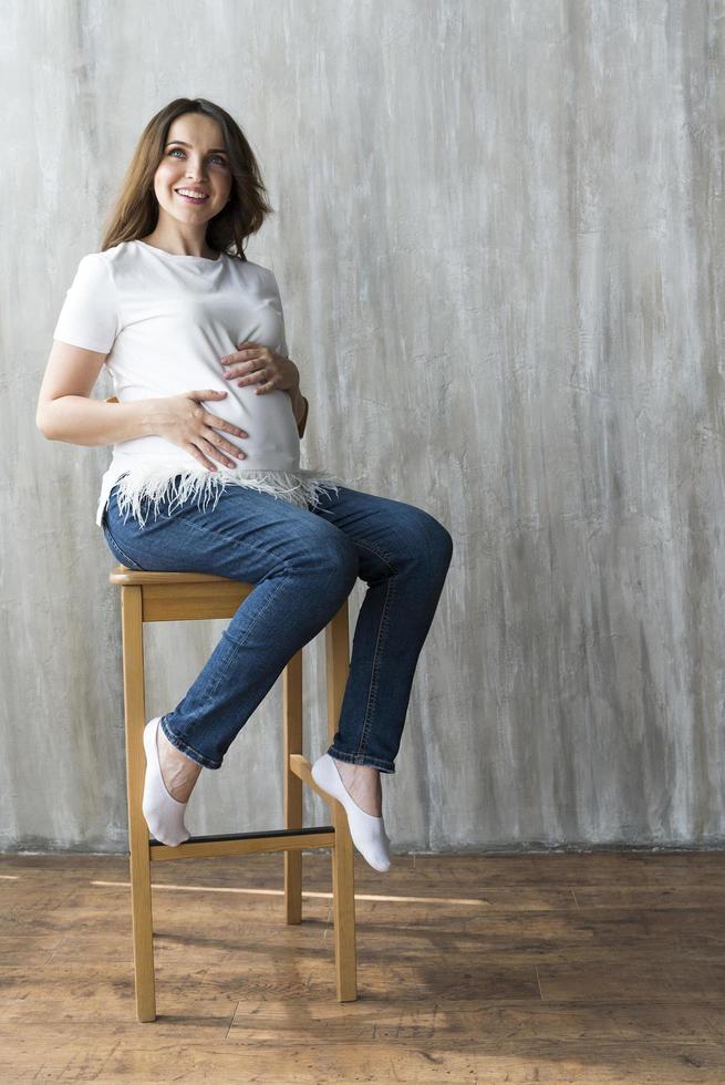 Pregnant girl on grey background. photo