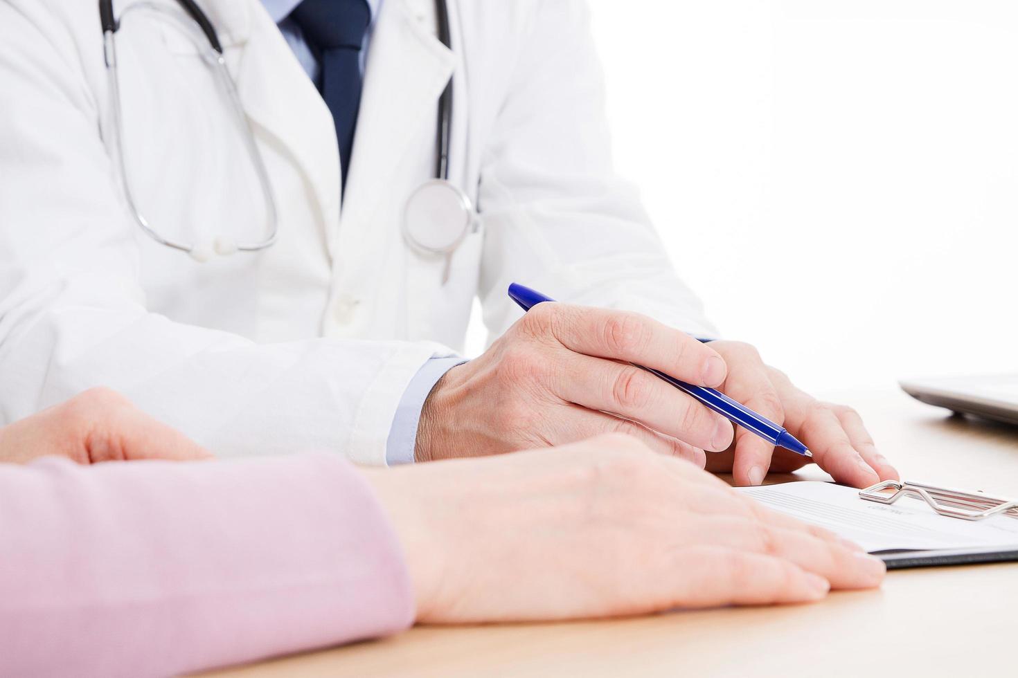 Doctor and patient are discussing something, just hands at the table, medical insurance. photo