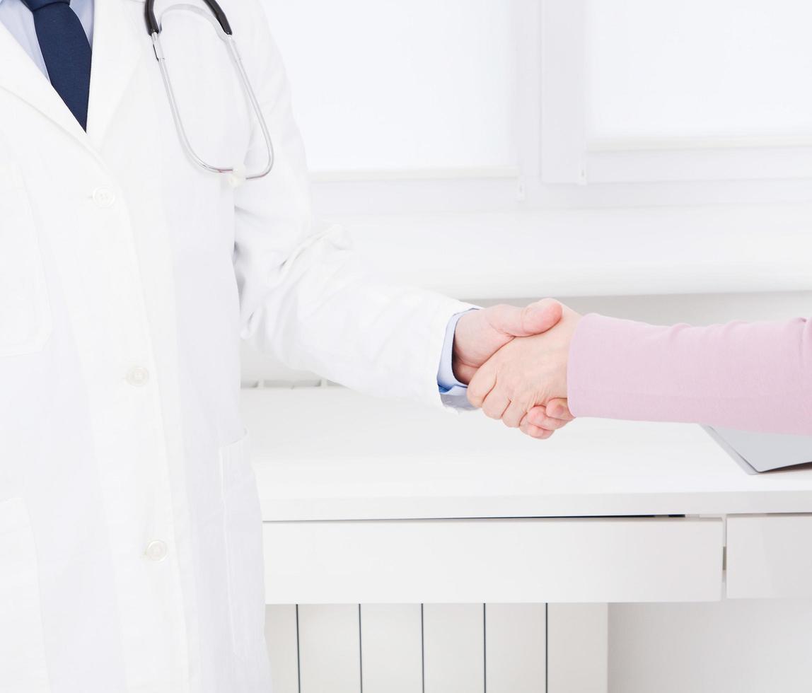 la mano femenina del médico sacude el brazo femenino de su paciente en la clínica, consultorio médico. concepto de salud, seguro de salud foto