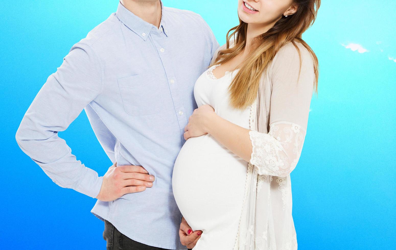 retrato de una pareja joven esperando al niño aislado de fondo azul, una pareja joven y atractiva madre embarazada y un padre feliz, una hermosa pareja joven esperando un bebé foto