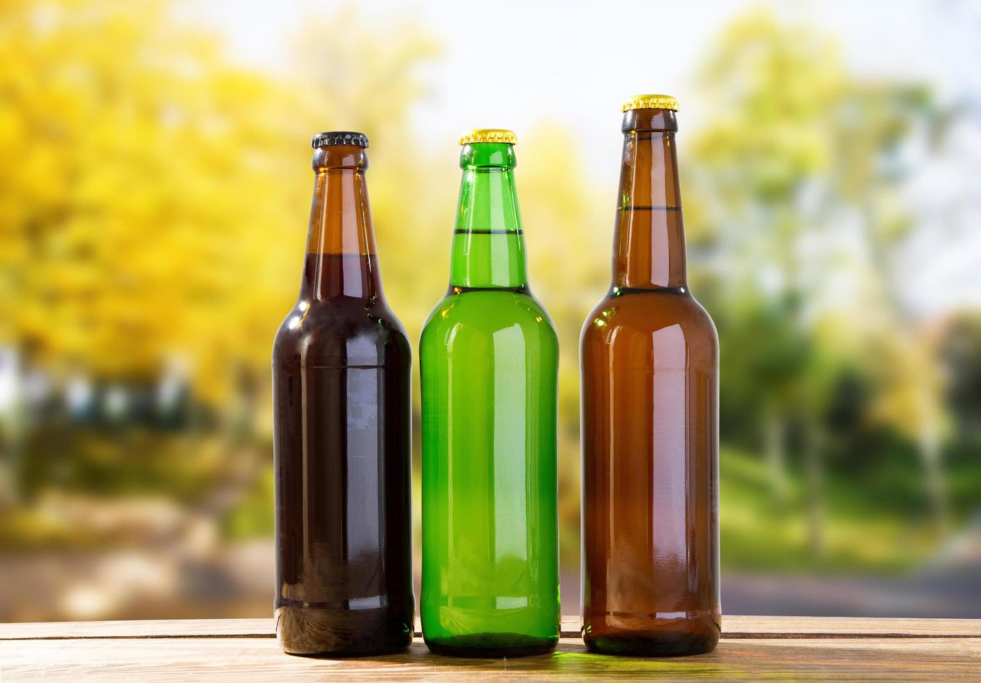 beer bottles on wooden table on blurred park background photo
