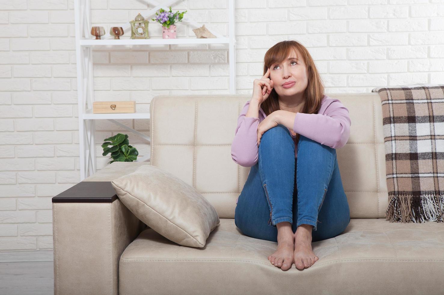 Beautiful brunette middle age woman dreaming and thinking at home. Mock up and copy space. Menopause photo