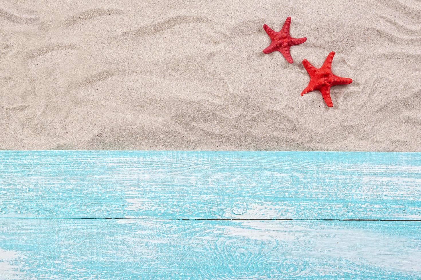 Summer concept - red starfish on the sand top view photo