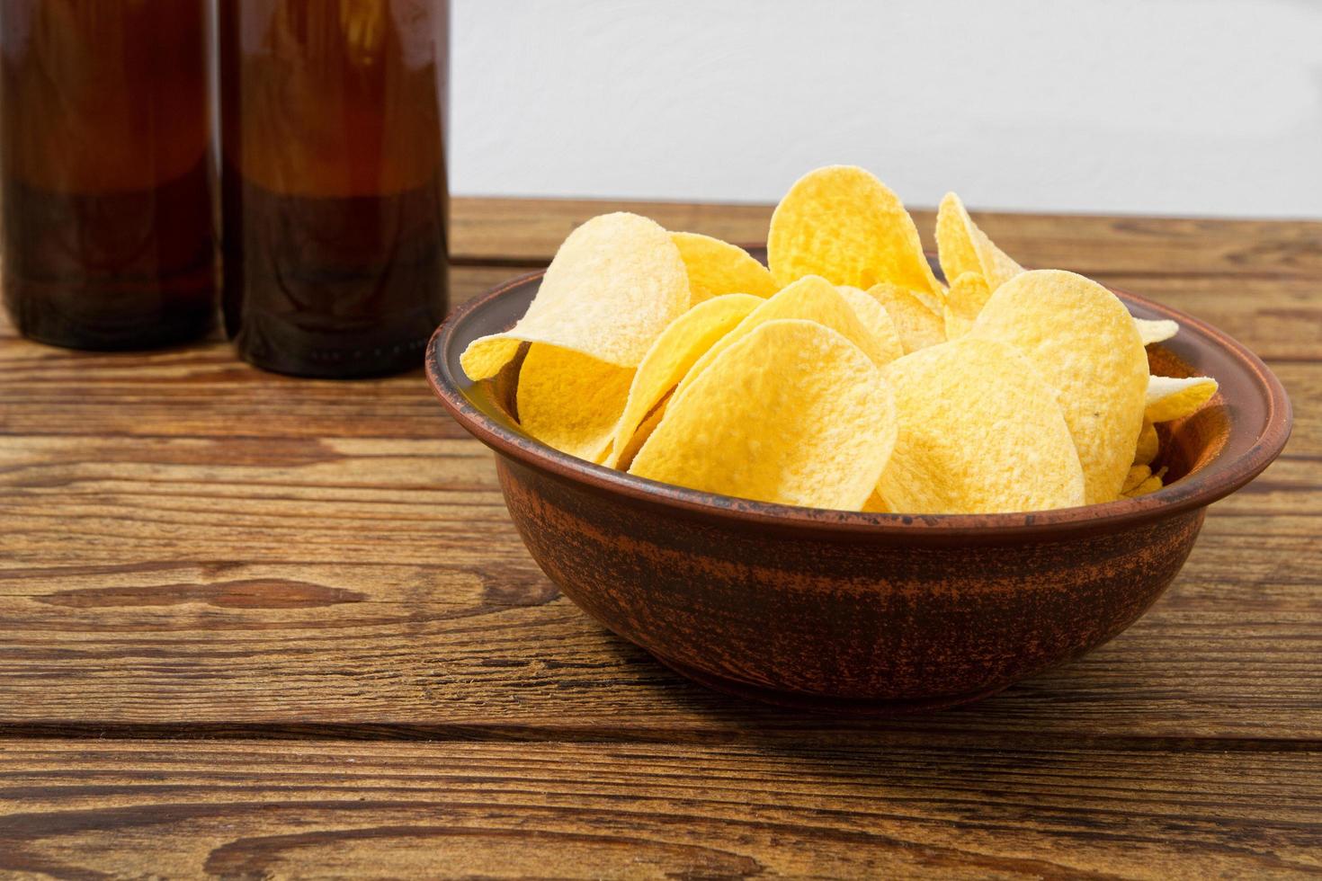 potato chips in plate on wooden table isolated on grey background photo