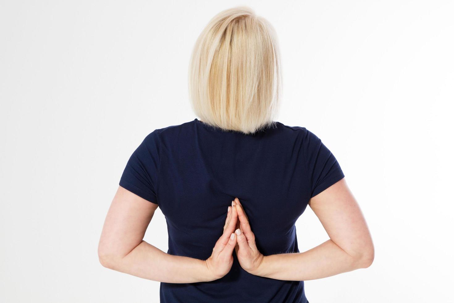 Back view of sporty woman standing in lotus pose isolated. Yoga and healthy lifestyle concept. hands closeup, middle-age woman meditates close up back. Reverse prayer hands mudra. Namaste yoga concept photo