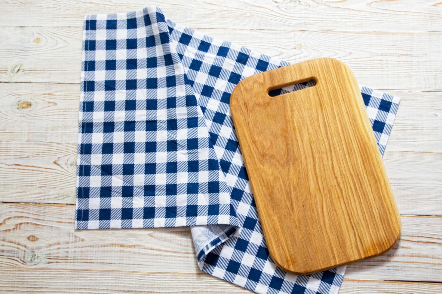 Top view of checkered napkin tablecloth on white wooden table. Empty cutting square board. photo