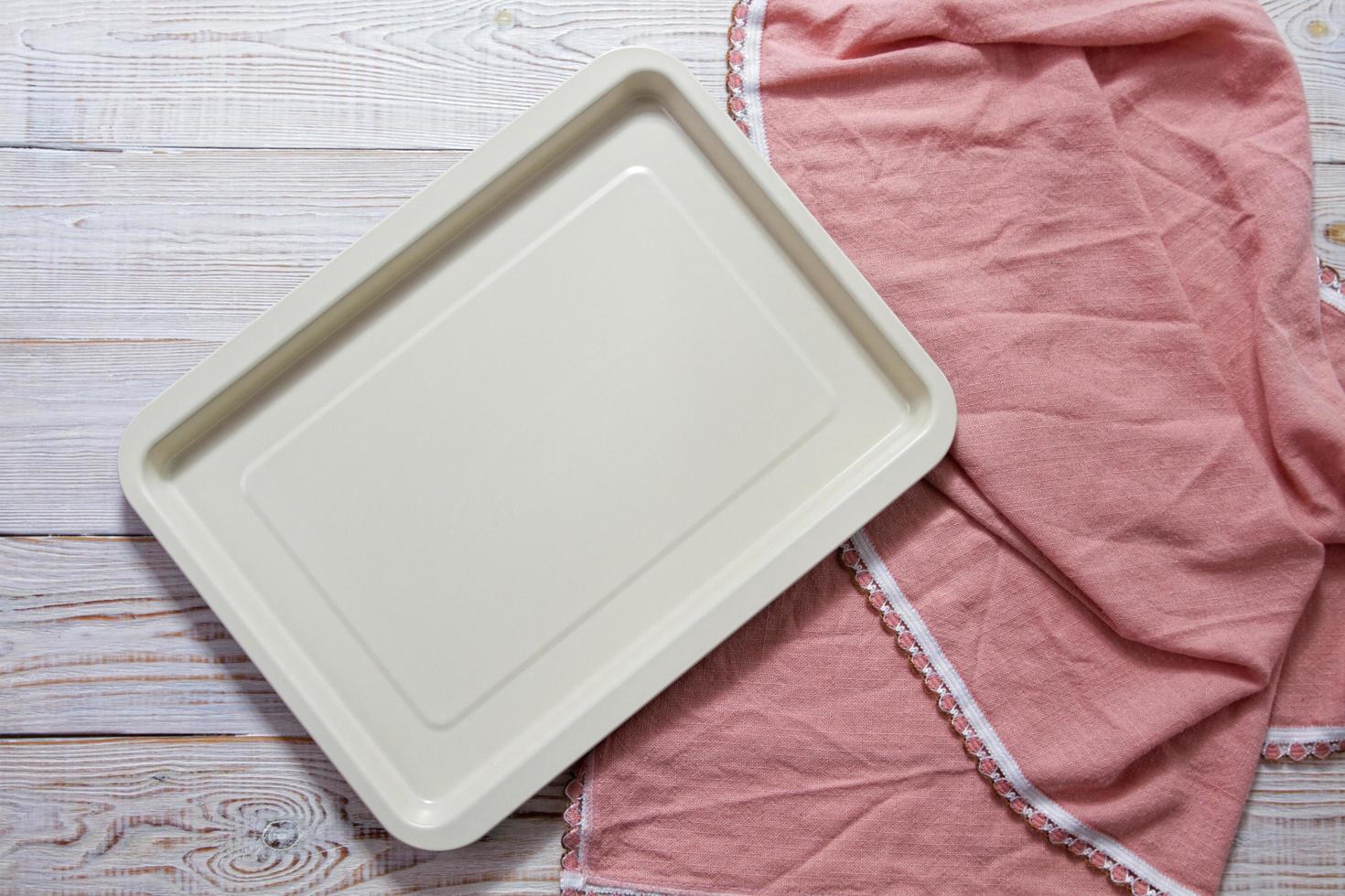 Empty baking tray with pink tablecloth top view on table photo