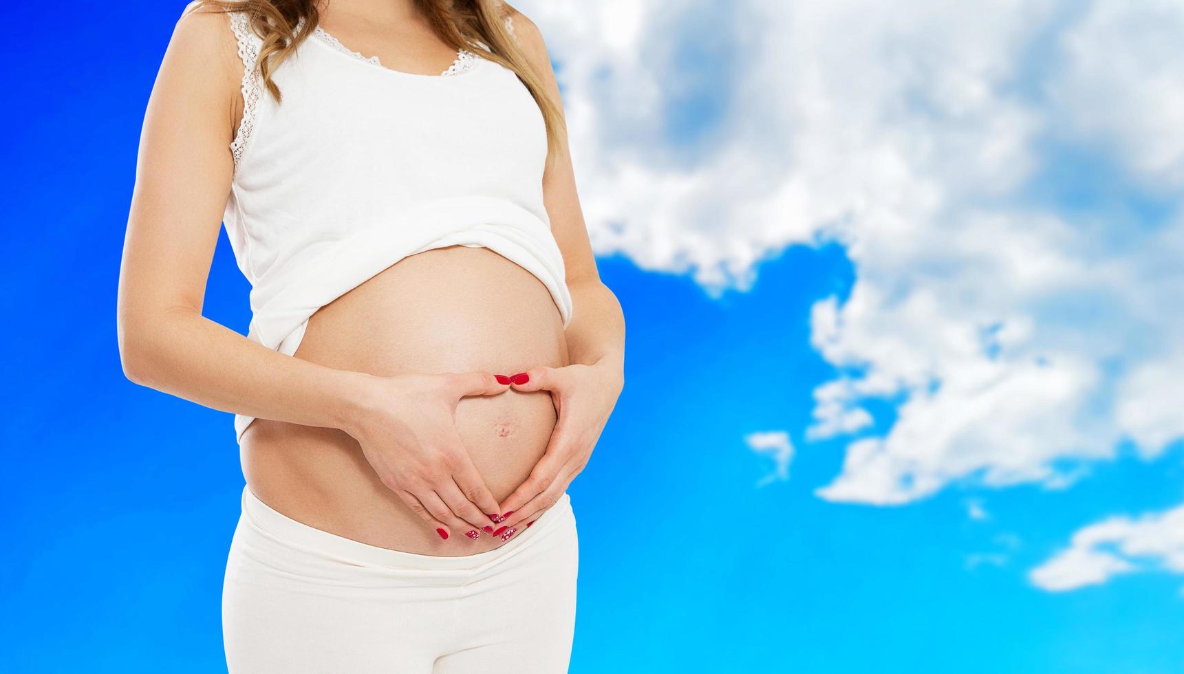 Pregnant woman in casual clothes isolated on blurred sky background, Pregnant woman in casual clothes isolated on blue background, pregnant beautiful lady, expecting baby photo