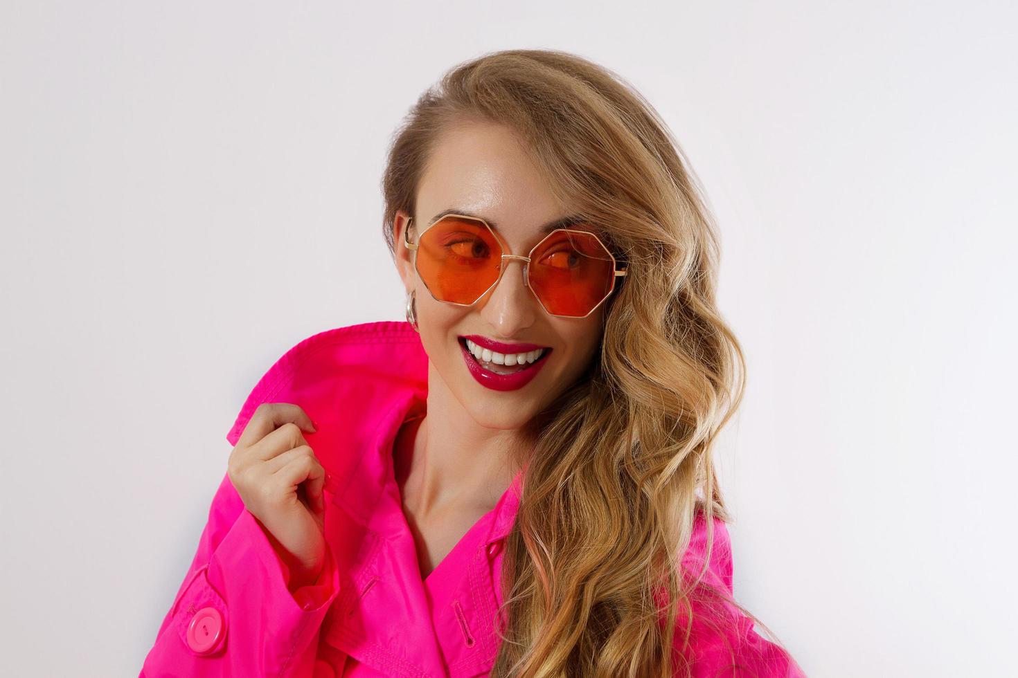 Happy, shock, excited woman face closeup. Girl in bright pink autumn clothes, red sunglasses isolated on white background, copy space. Beautiful female surprised, cheerful. Fun funny model screaming photo