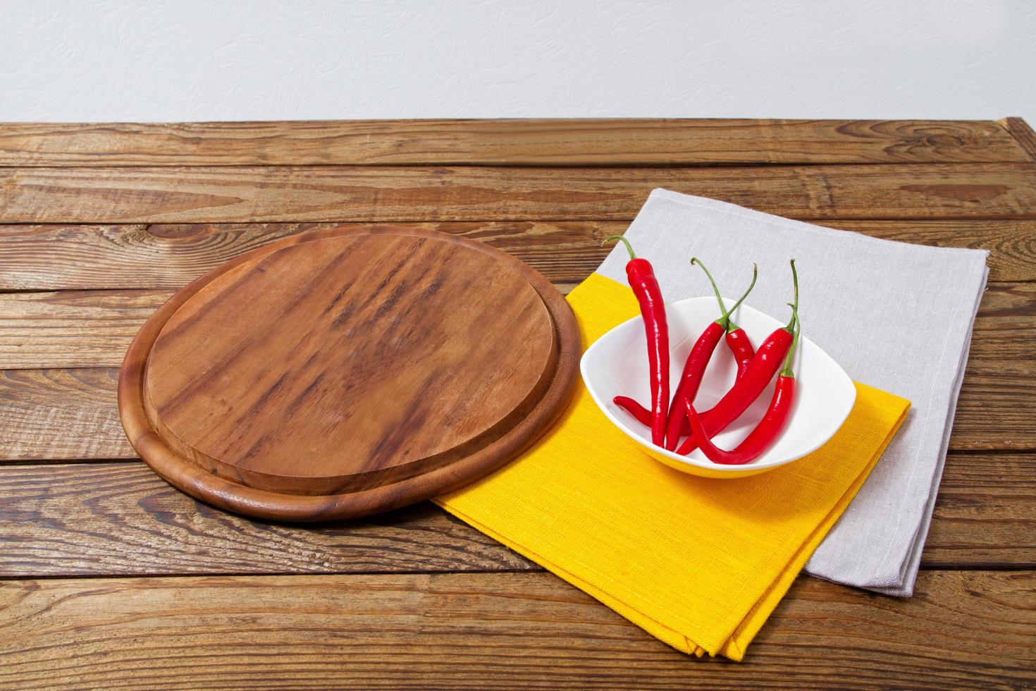 empty pizza desk, hot pepper and yellow and grow napkins on wooden table, food background, top view photo