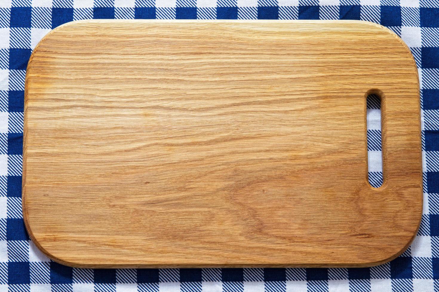 primer plano de la tabla de cortar de madera en la servilleta de mantel a cuadros foto