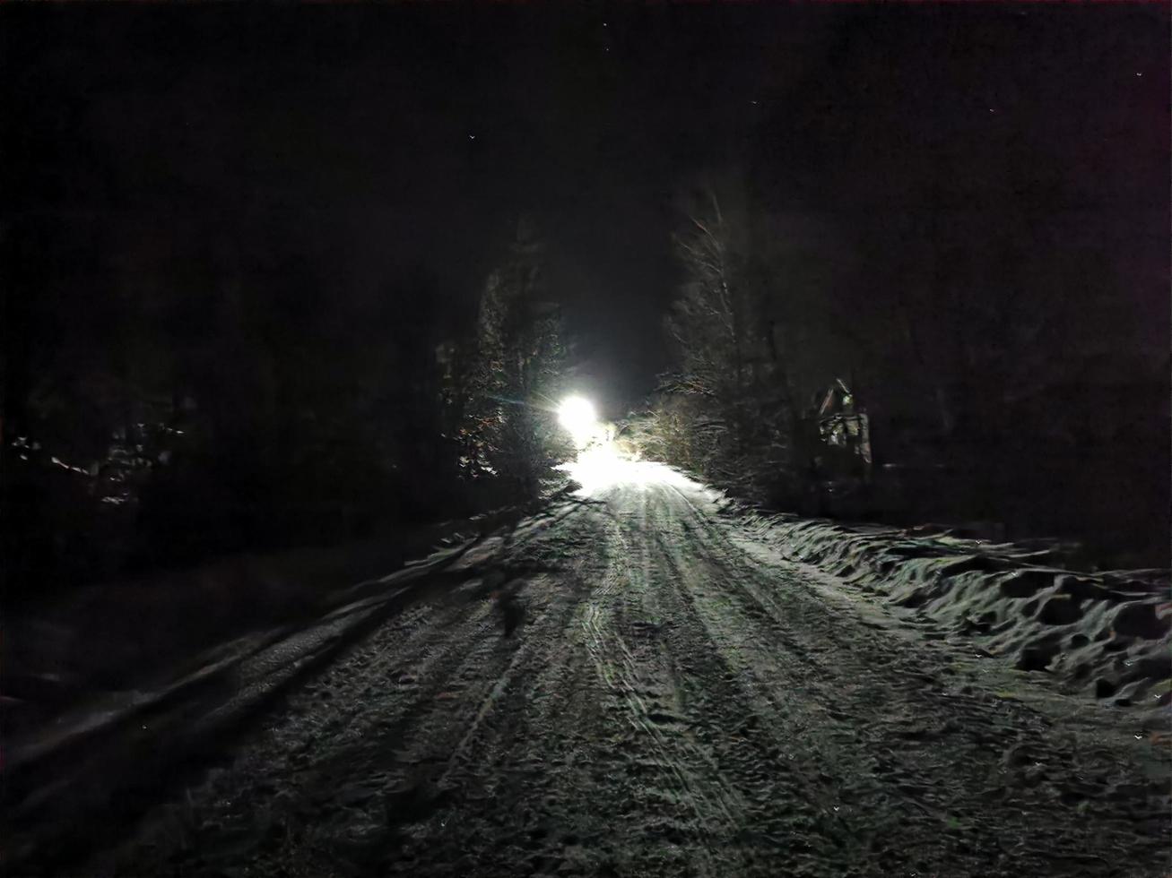 snowy road on a moonlit winter night in the village photo