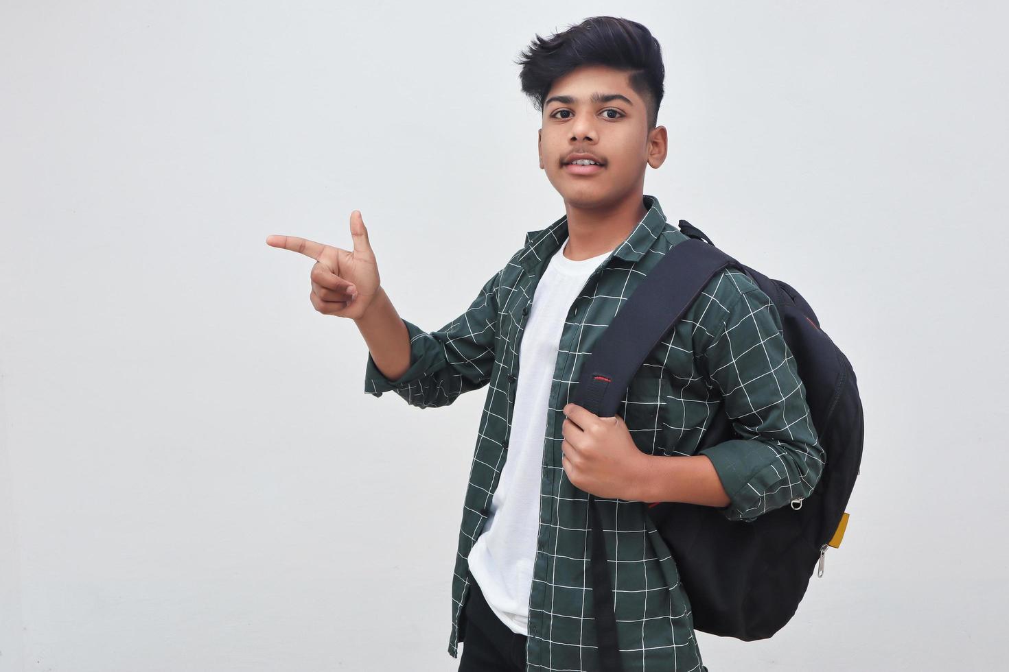 Handsome Indian college boy pointing with hand on white background. photo