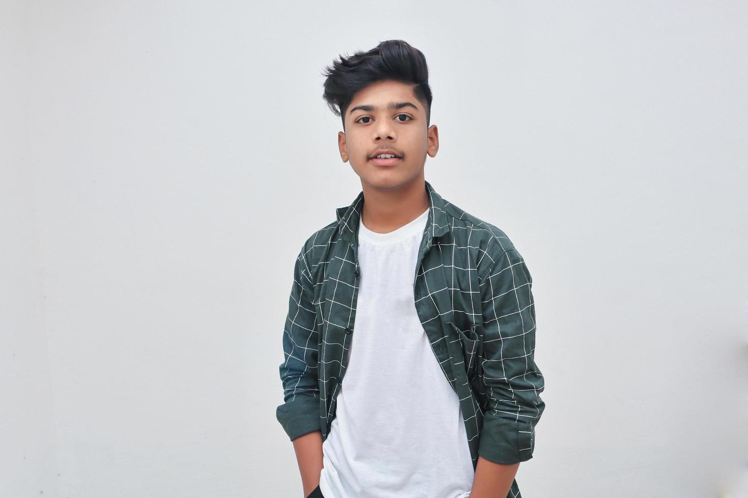 Handsome Indian young boy standing on white background. photo