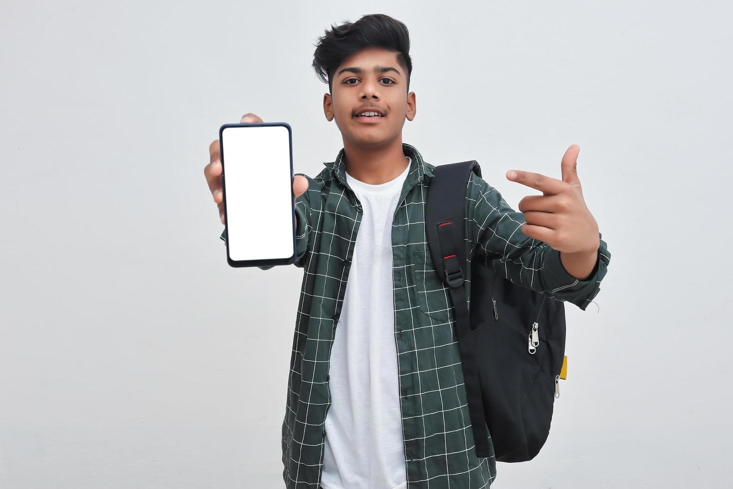 Young indian collage boy showing smartphone screen on white background. photo