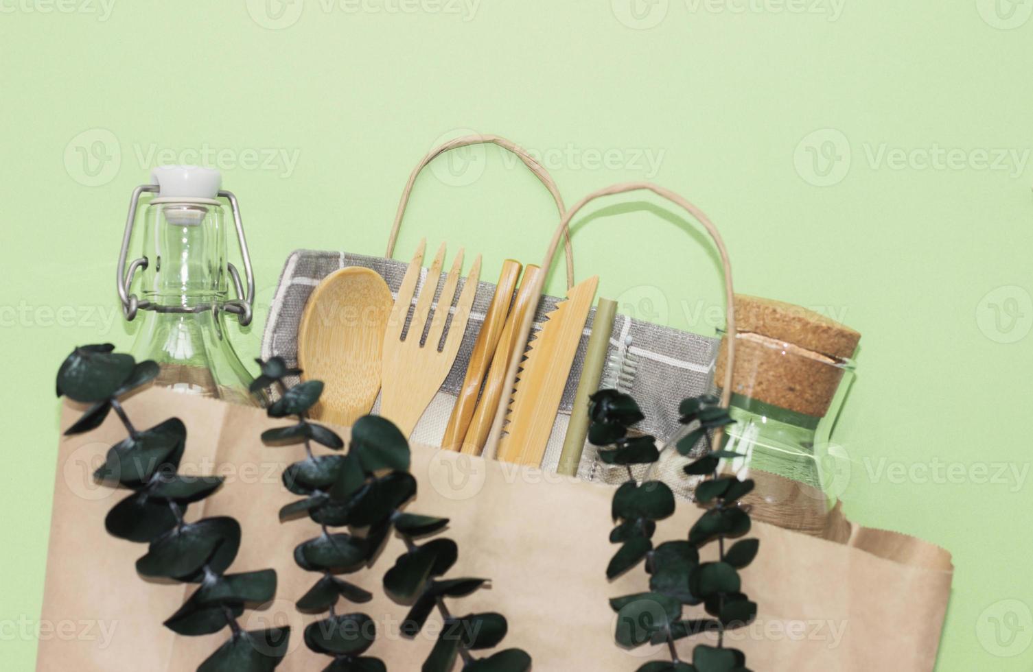 set of bamboo cutlery and glass bolltes in craft paper bag. eco friendly kitchen supply and zero waste concept. photo