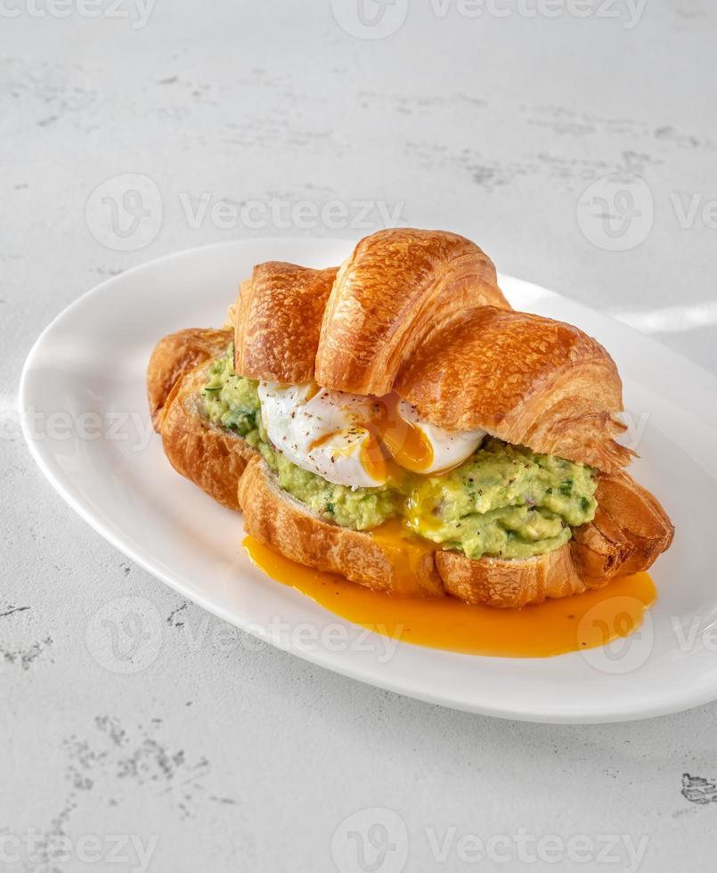 Croissant with guacamole and poached egg photo