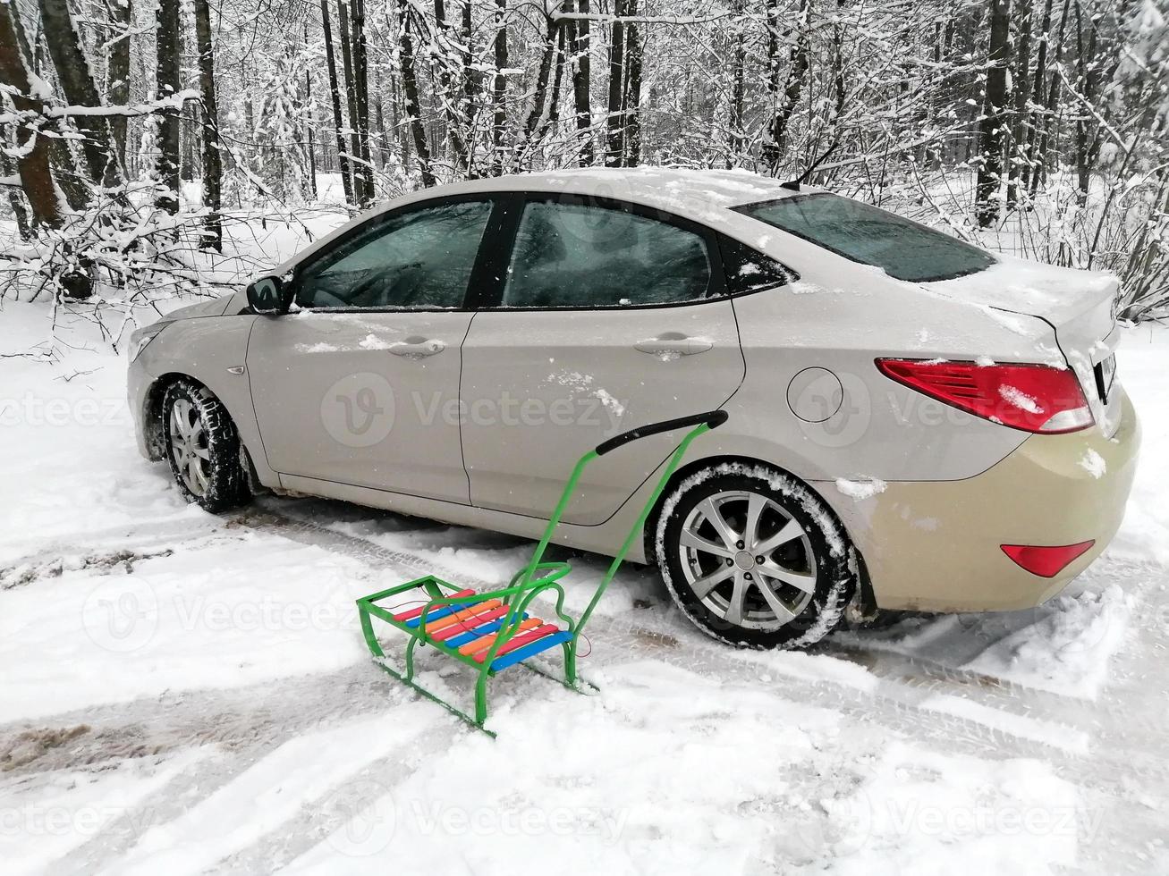 A passenger car in the snow, parked in a city park, against a background of gray trees. photo