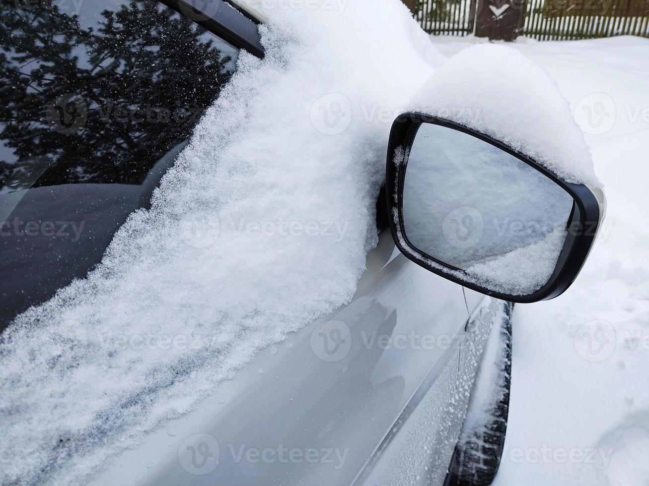 A passenger car covered with snow. Side mirror in the snow. photo