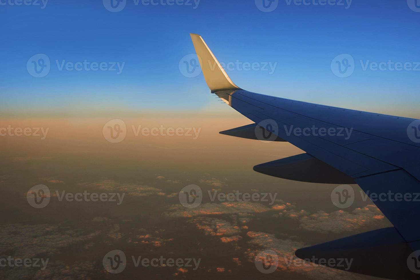 View to the wing of airplane in the sky during sunset. Travel and transportation concept photo