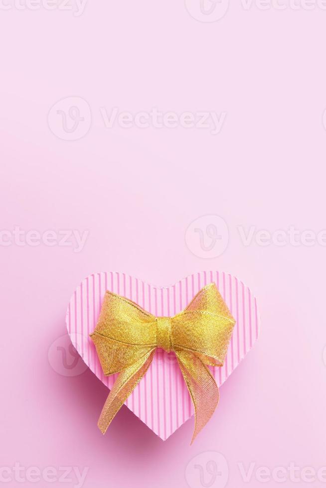 Heart-shaped box pink color with golden bow - gifts for valentines day, birthday, mothers day with copy space photo