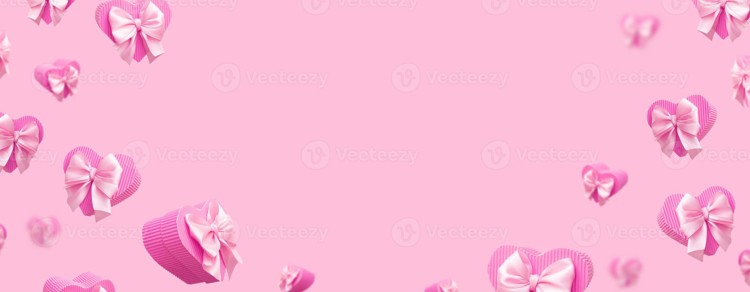 banner con cajas de regalo en forma de corazón rosa voladoras aisladas sobre fondo rosa. tarjeta de felicitación o pancarta monocromática de moda del día de san valentín foto