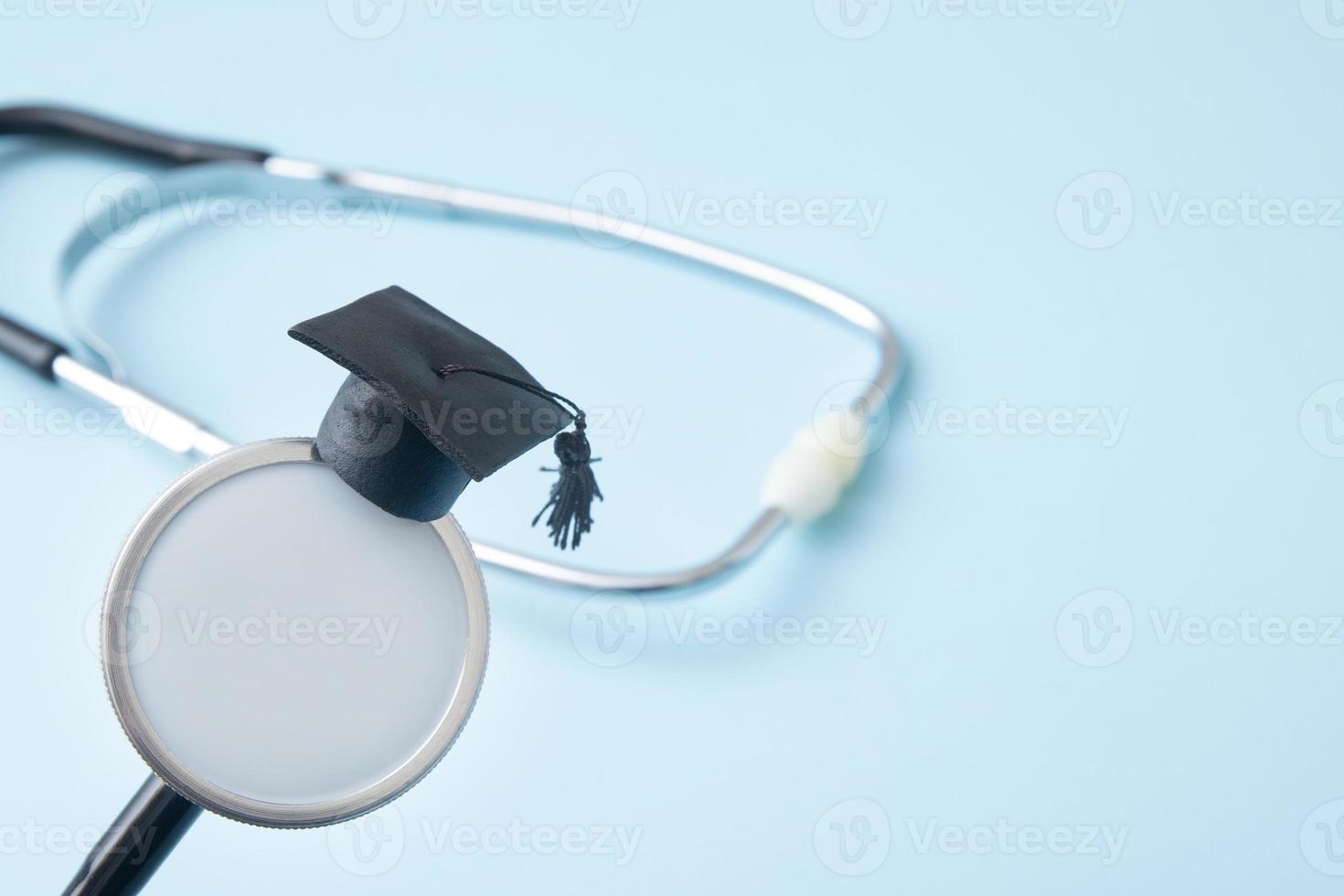 Graduation hat on doctor stethoscope mock up, blue background with copy space. Medical school, health care education or doctor's university degree concept photo