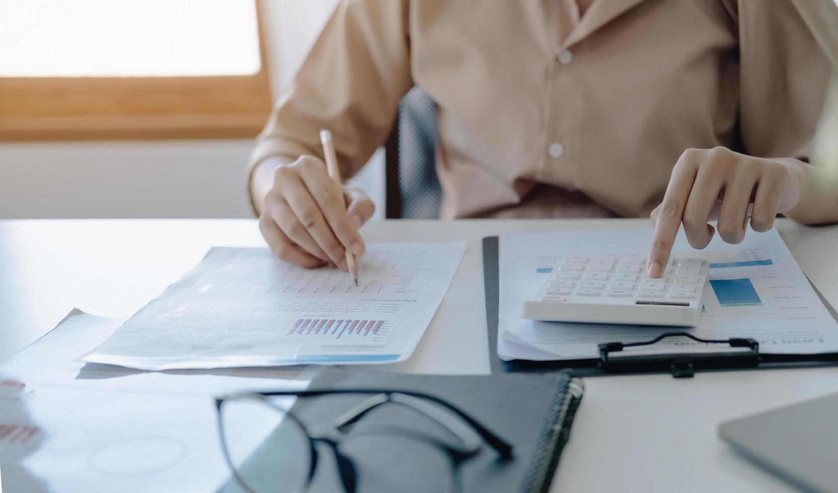 Mujer de negocios de cerca con calculadora y computadora portátil para hacer finanzas matemáticas en un escritorio de madera en la oficina y el fondo de trabajo empresarial, impuestos, contabilidad, estadísticas y concepto de investigación analítica foto