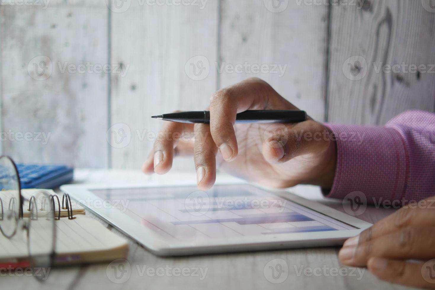 La mano del hombre trabajando en una tableta digital en el escritorio de la oficina, utilizando un gráfico creado por uno mismo foto