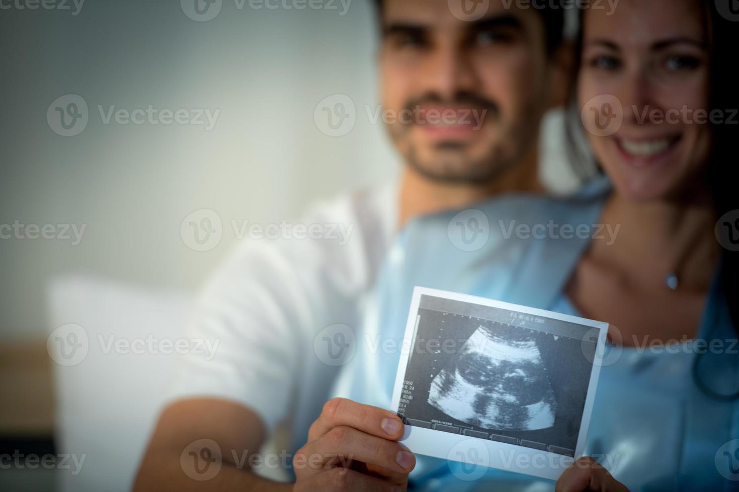 The happiness of a pregnant woman and her husband in the bedroom with the ultrasound film photo