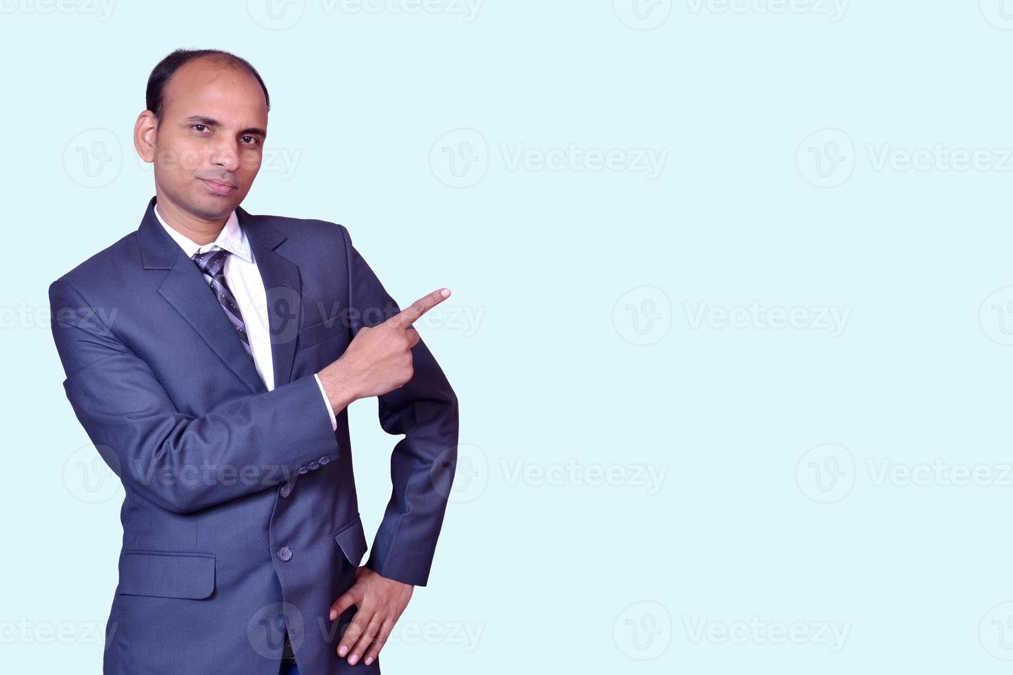 Young smiling Indian businessman pointing with finger upward image photo