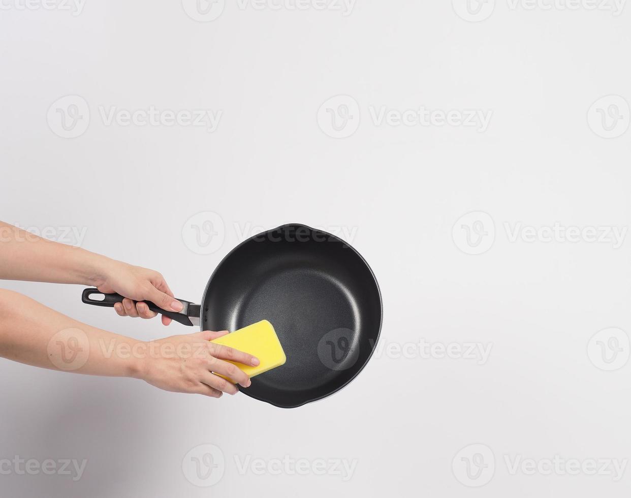 Hand cleaning the non stick pan with handy dish washing sponge photo