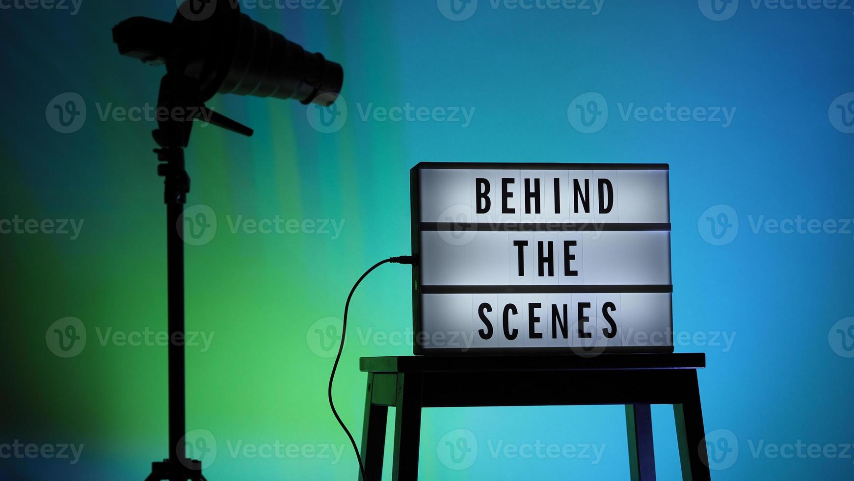 Caja de luz de tablero de película en escalera de estudio y trípode de luz snoot sobre fondo degradado de colores. foto