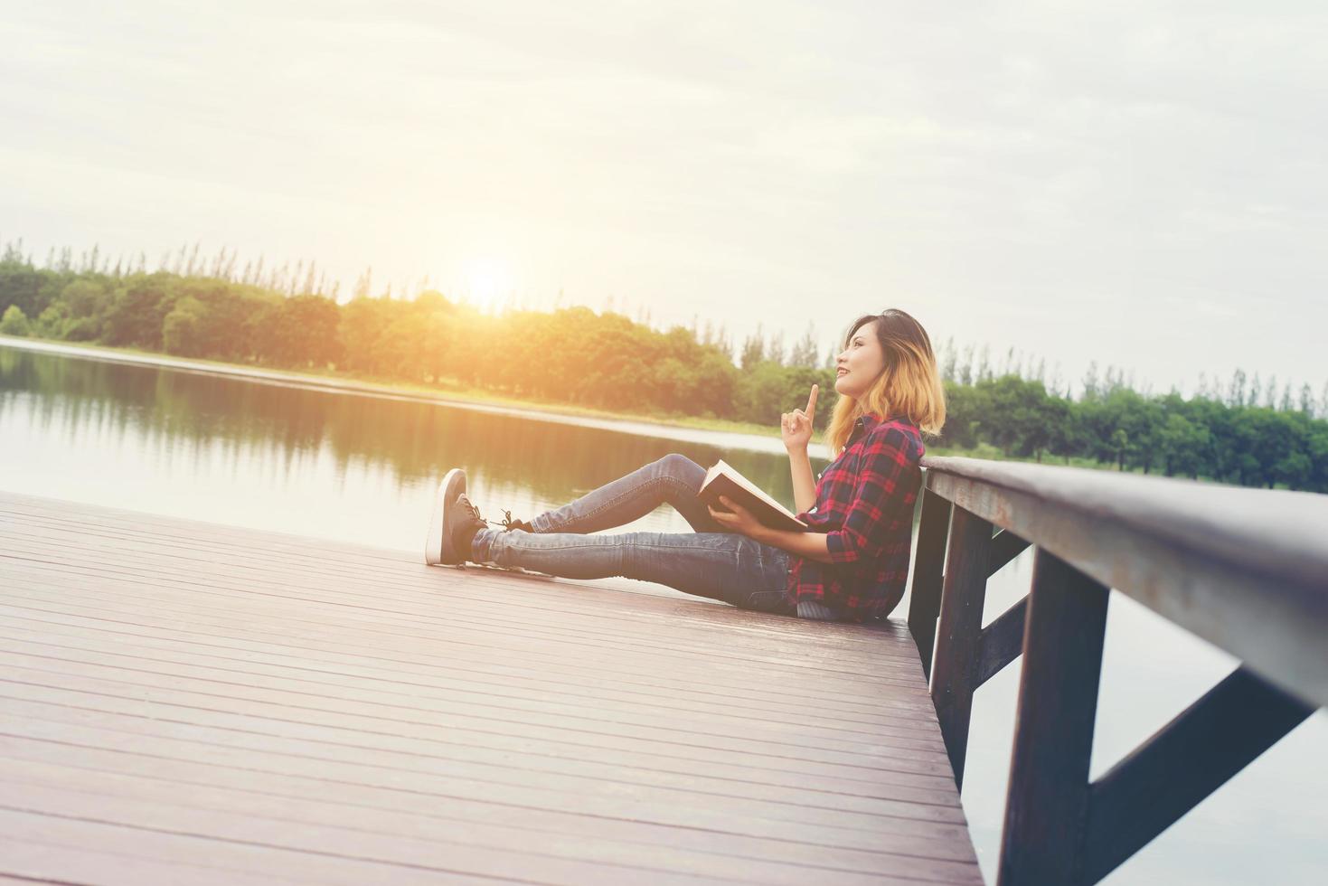 young beautiful hipster woman relaxing sitting on pier reading book. photo