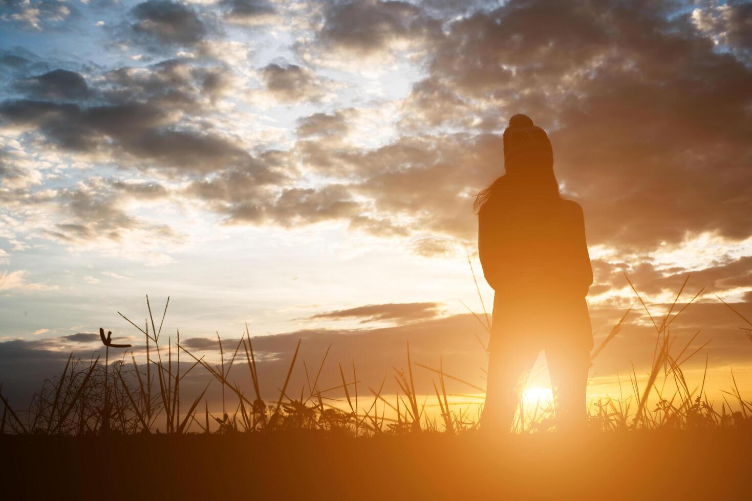 Silhouette of woman standing on field during sunset. photo