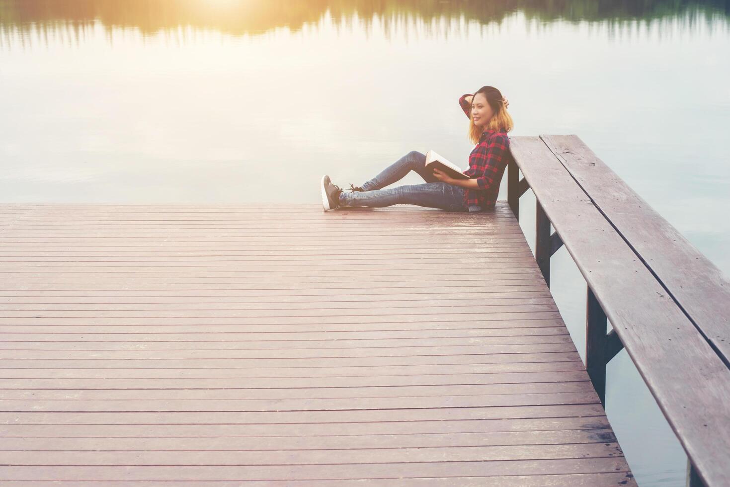 joven hermosa mujer hipster relajándose sentada en el libro de lectura del muelle. foto