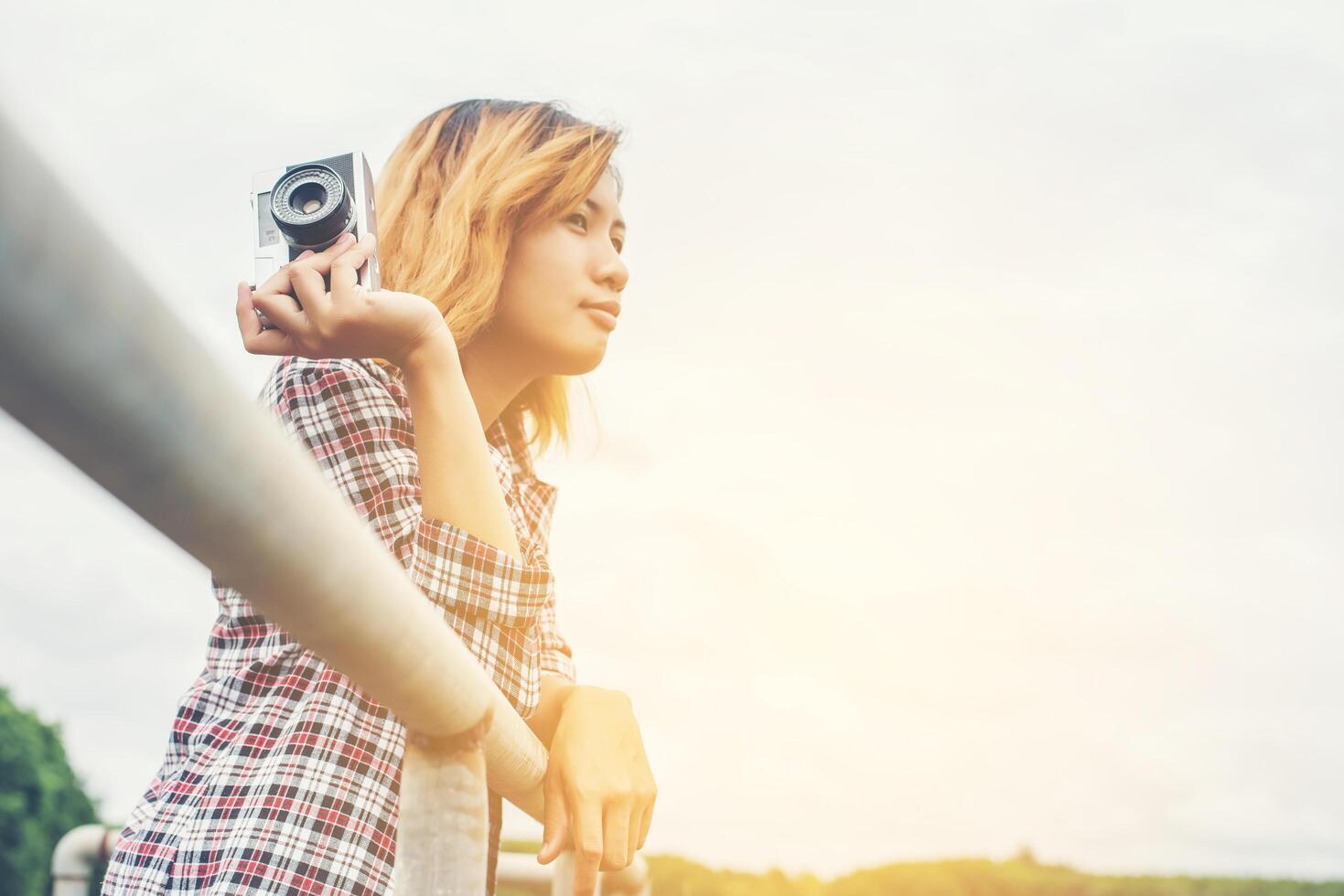 Young beautiful hipster woman holding retro camera outside with nature enjoy fresh air. photo