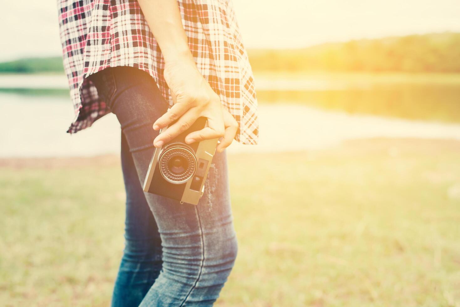 Young beautiful hipster woman holding retro camera outside with nature enjoy fresh air. photo