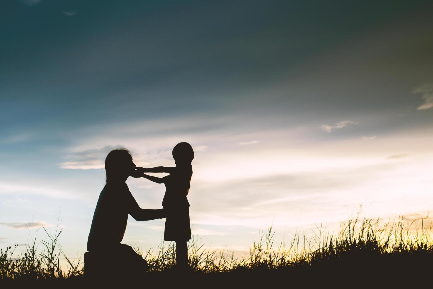 Mother encouraged her son outdoors at sunset, silhouette concept photo