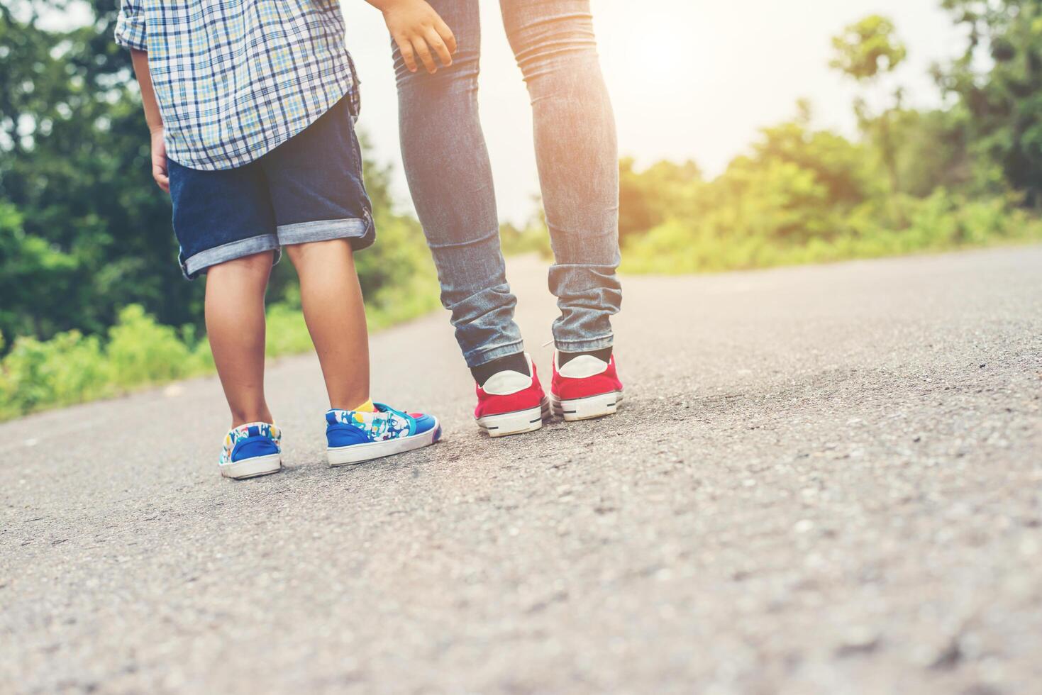 la madre está caminando por la carretera con su pequeño hijo, los pies de la madre y el niño. foto