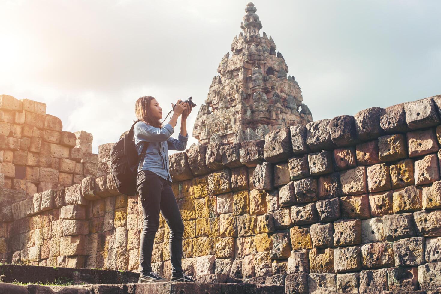 joven y atractiva mujer fotógrafa turista con mochila que viene a tomar fotos en el antiguo templo de peldaño fantasma en tailandia.