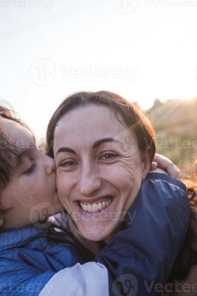 niño besa y abraza a mamá, feliz maternidad foto